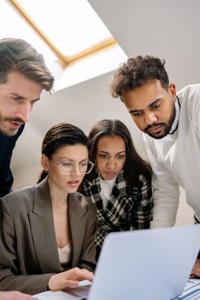 A diverse group of professionals collaborating on a laptop at work.